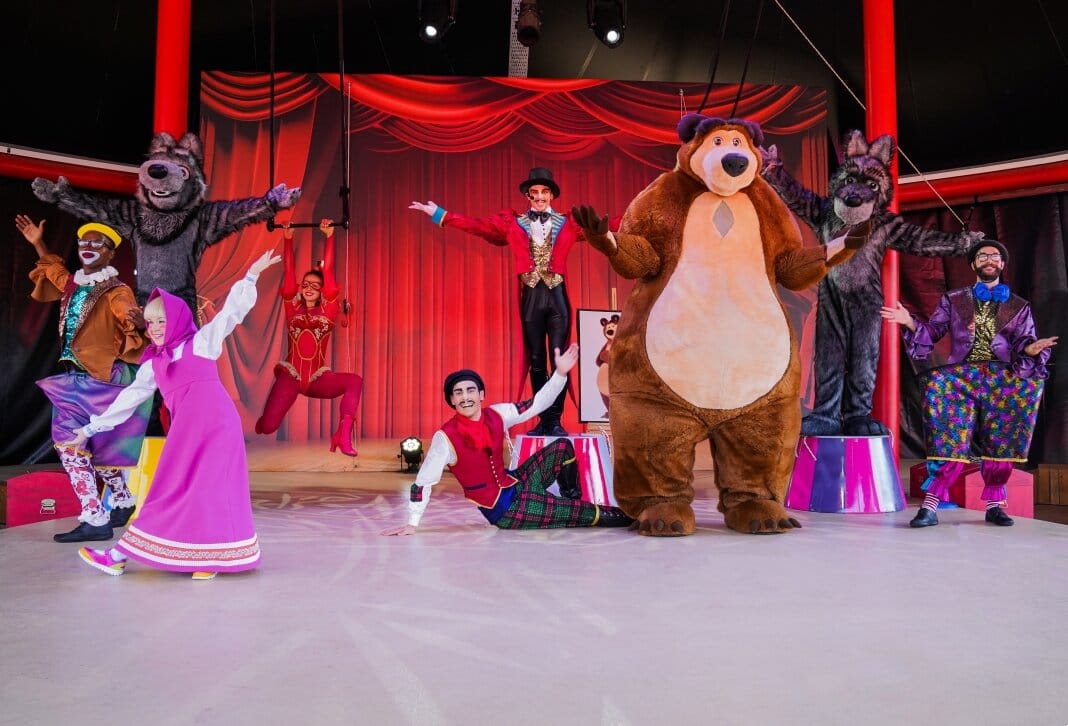 Characters including Masha and The Bear perform on a stage with circus performers