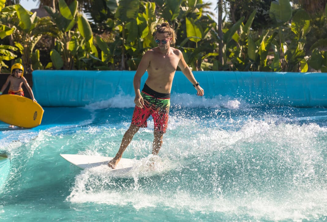 Young man surfing on the artificial wave pool simulator at The Land of Legends water park