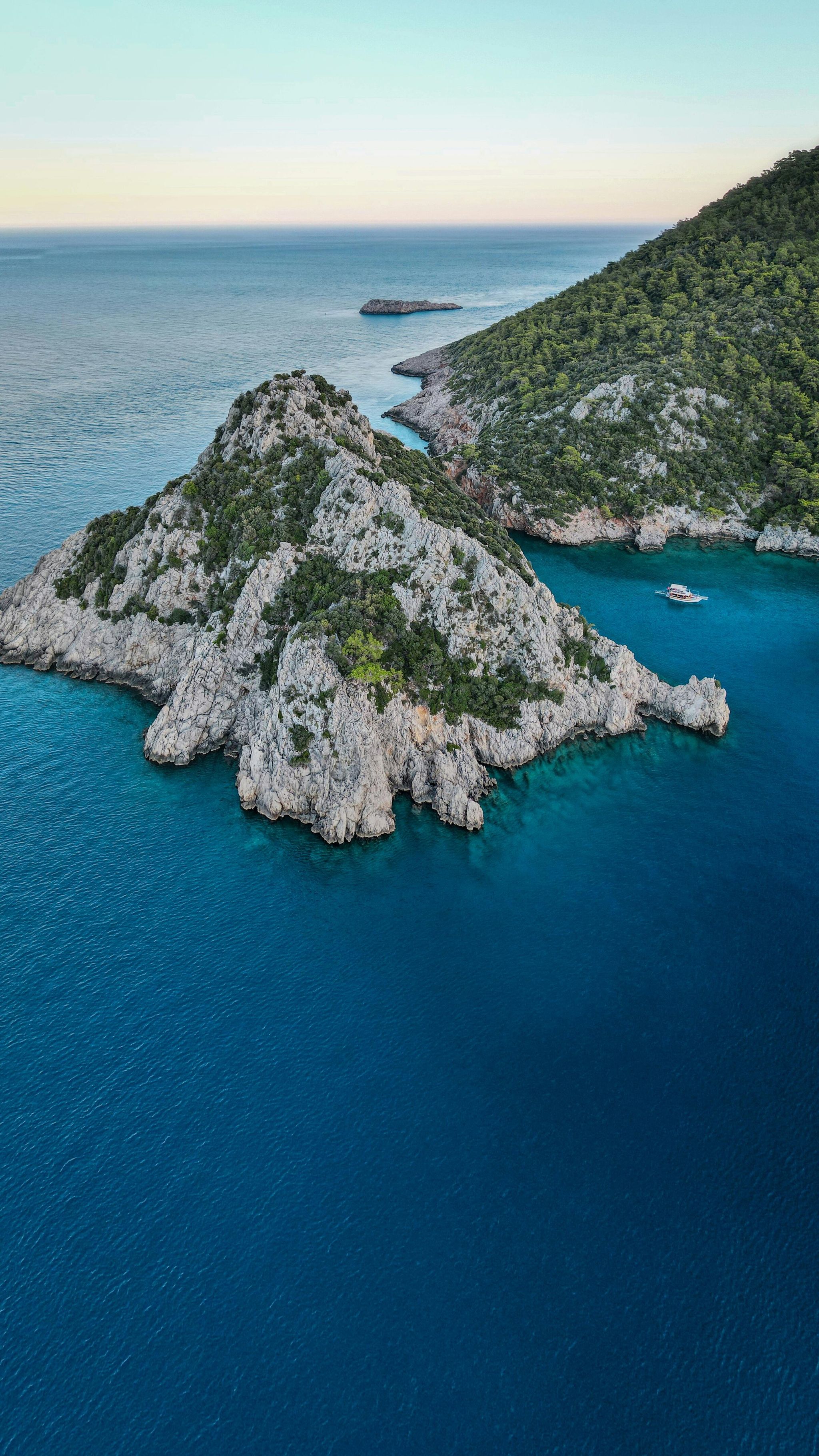 Tourists swimming in the calm emerald sea around excursion boats in a Bay