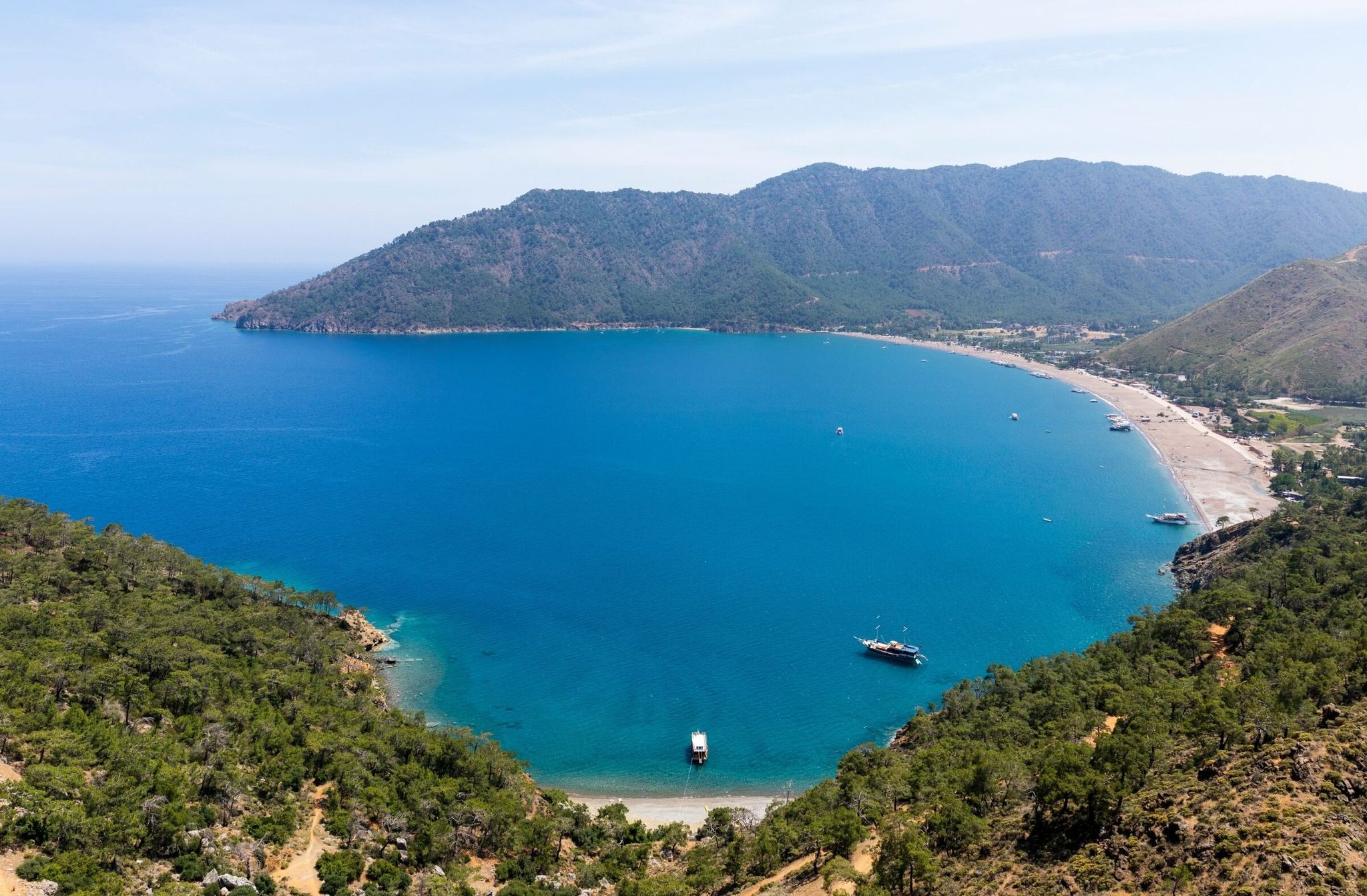 Panoramic view of the secluded pebble beach and steep rocky cliffs at Porto Ceneviz Cove