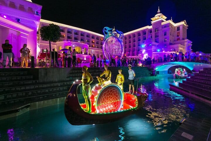 An elaborate boat with glowing A brightly lit canal walkway lights moves along a canal at a luxury resort