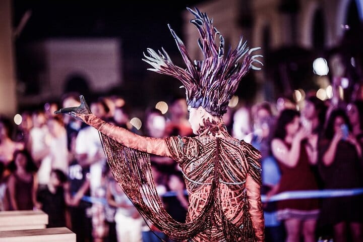 Performance in a striking headdress with fringed copper costume.