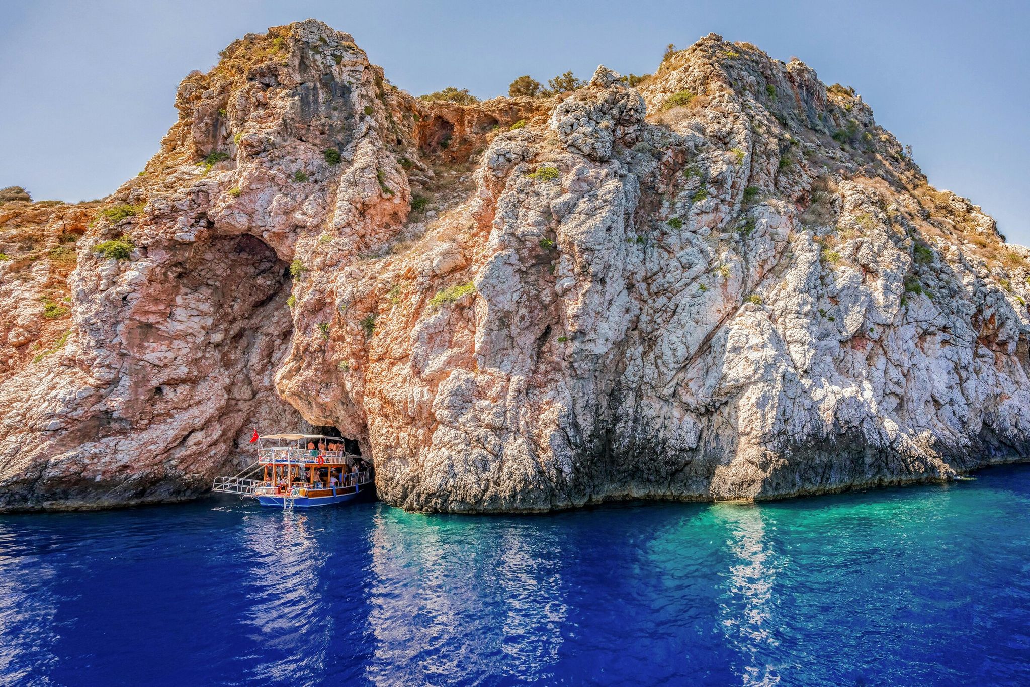 Traditional Turkish wooden gulet sailing past the dramatic coastal cliffs of Porto Ceneviz near Adrasan
